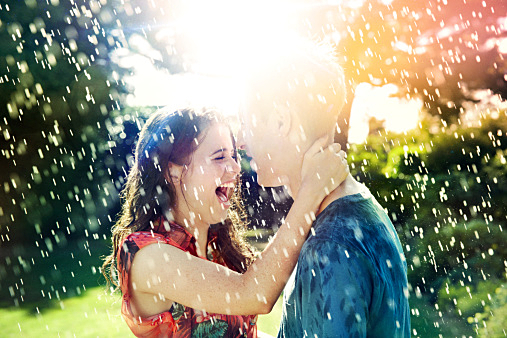 Teenage couple laughing in rain